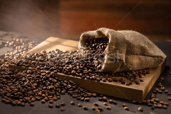 stock-photo-spilled-coffee-beans-in-bag-on-wood
